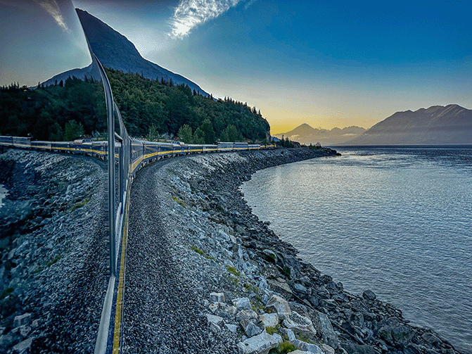 train traveling along the mountains and water